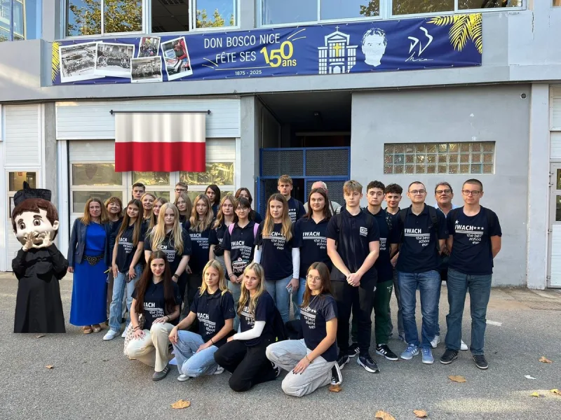 Élèves polonais accueillis à Don Bosco Nice, avec la mascotte de Don Bosco et le drapeau de la Pologne, devant la bannière des 150 ans