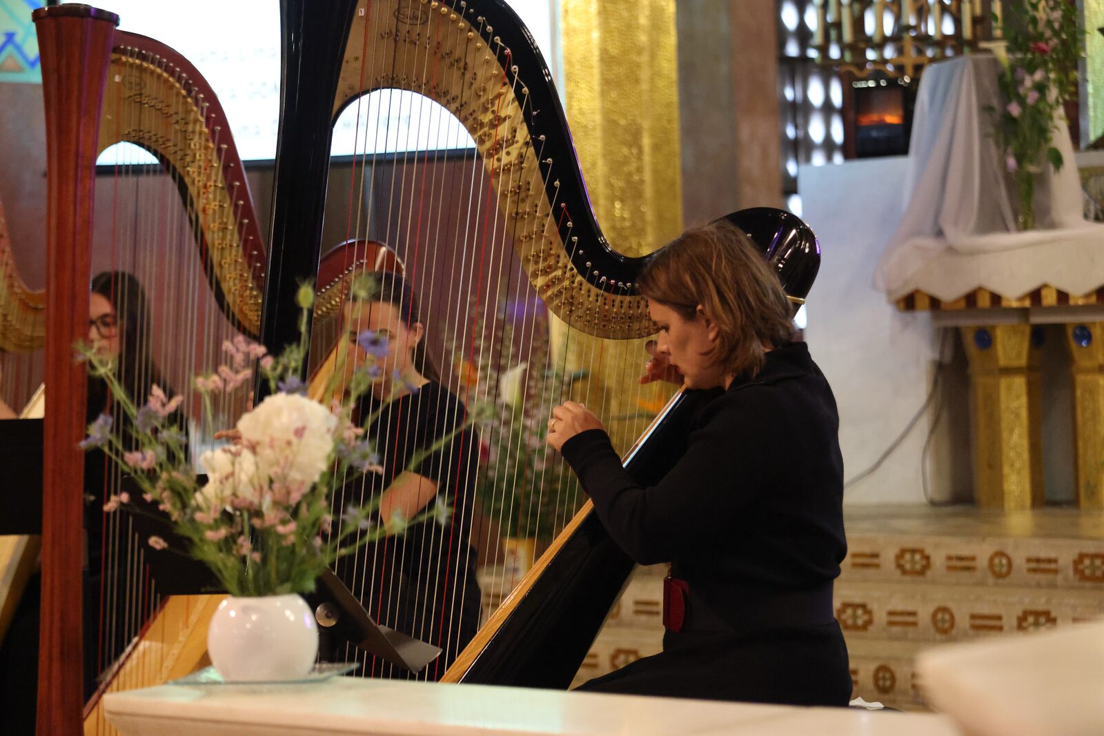 Une harpiste en concert, un bouquet de fleurs au premier plan