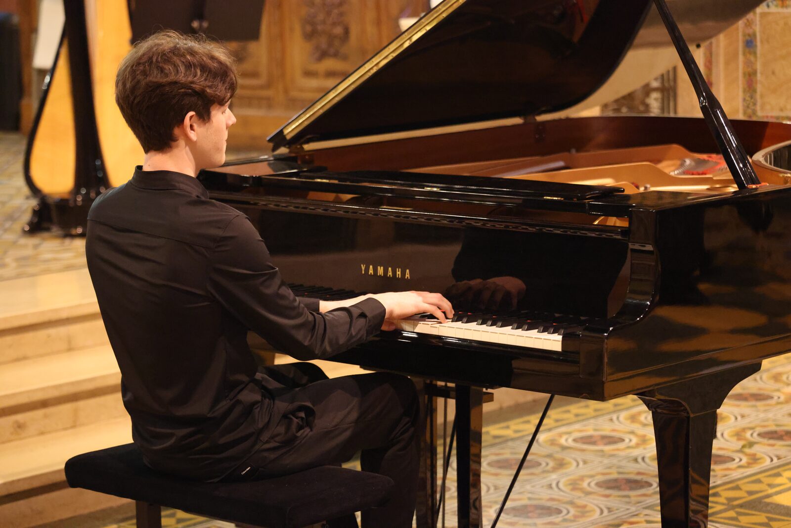Un pianiste de profil au piano à queue, dans l’église
