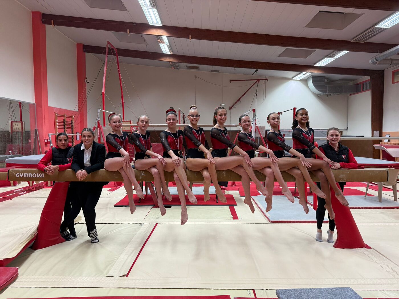 Les gymnastes du Cavigal Nice assises sur la poutre, en justaucorps