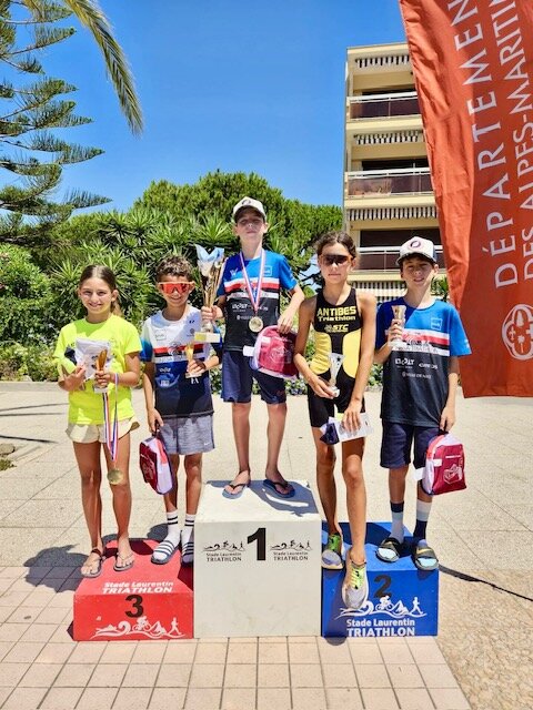 Six jeunes triathlètes sur le podium, coupes et médailles en main