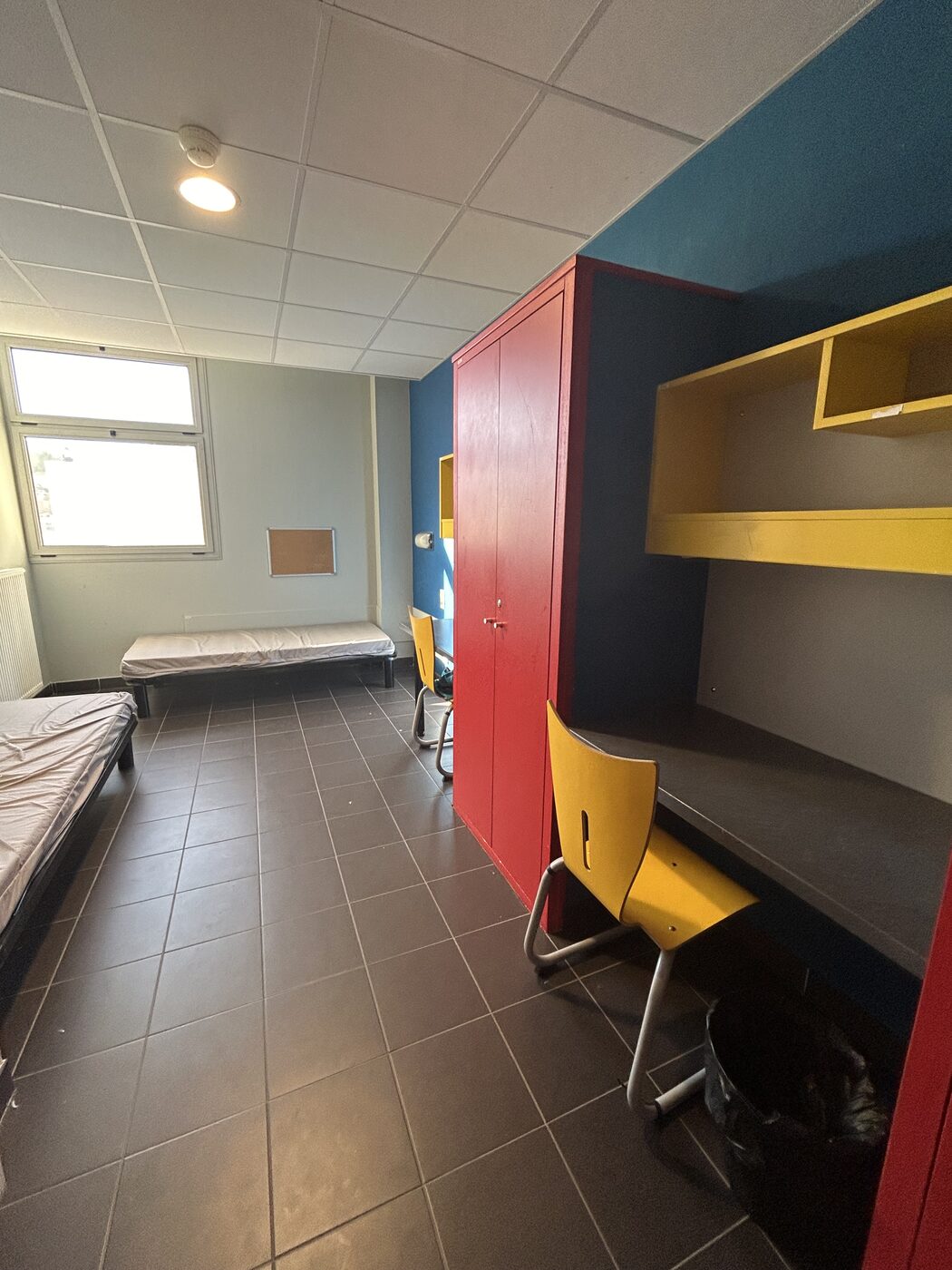 Le bureau jaune et les rangements d’une chambre de l’internat