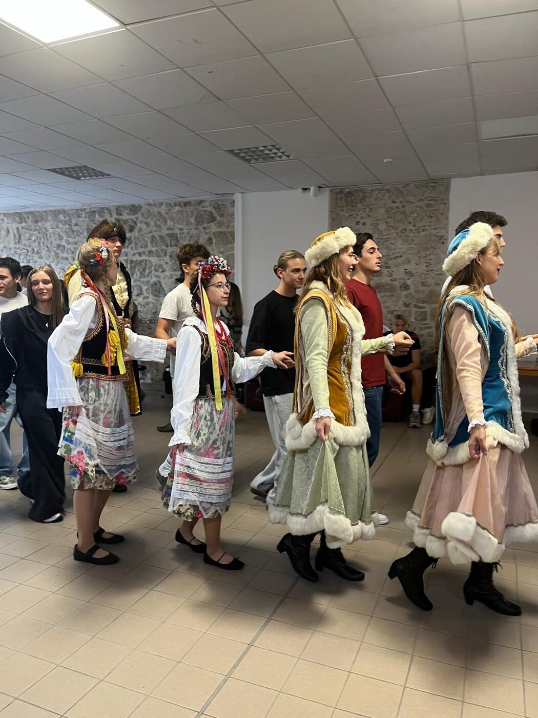 Des élèves en costume traditionnel polonais dansent dans une salle de l’établissement