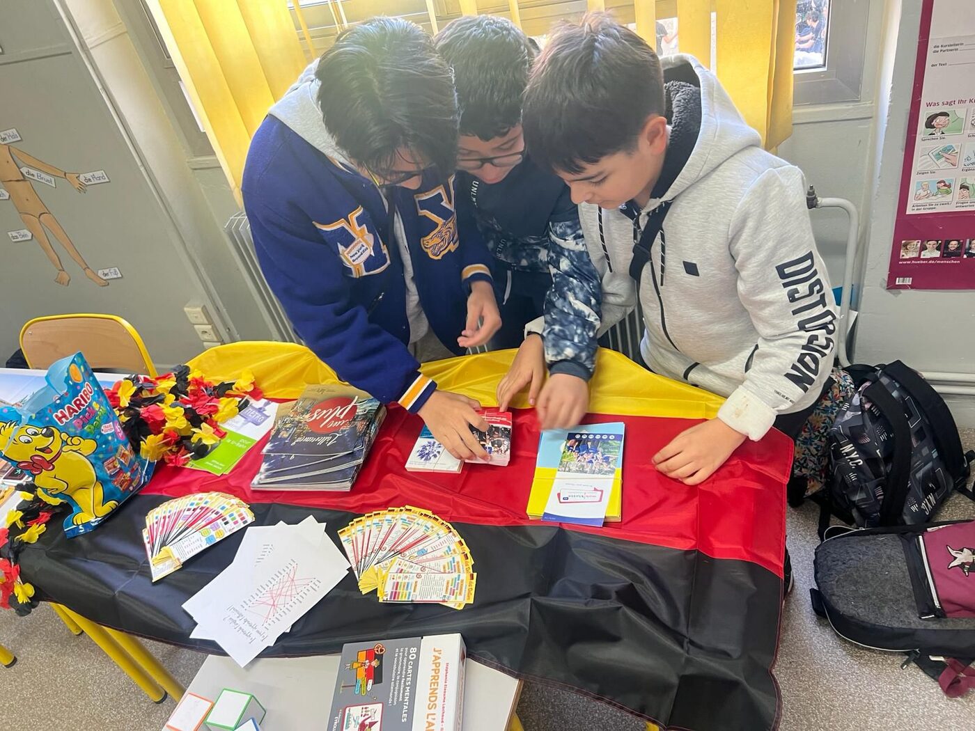 Deux élèves remplissent des cartes sur une table aux couleurs d’un drapeau