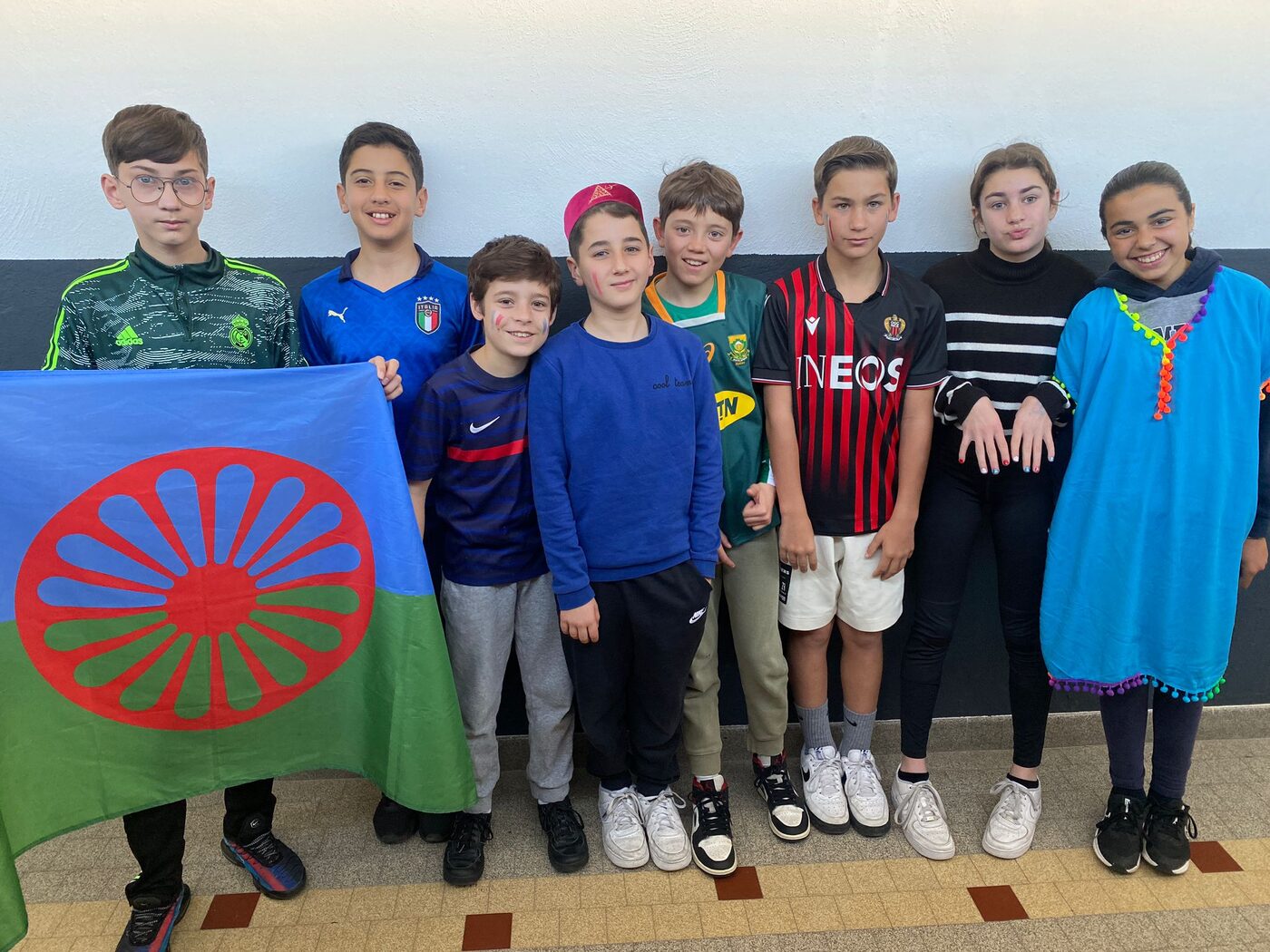 Des collégiens posent avec des drapeaux et des maillots de plusieurs pays