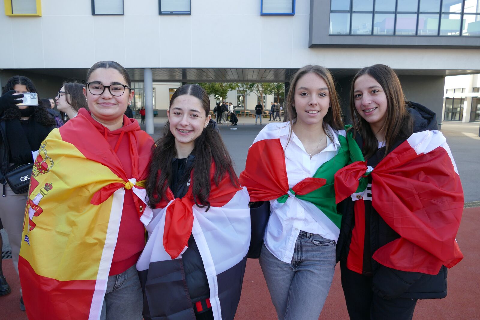 Quatre lycéennes drapées dans les drapeaux de plusieurs pays, dans la cour de l’établissement