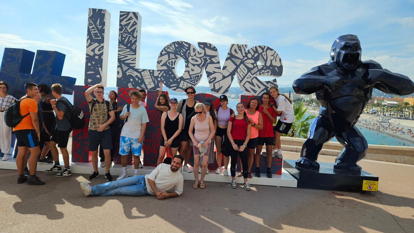 Élèves accueillis à Nice, assis et debout devant les lettres « I love Nice »