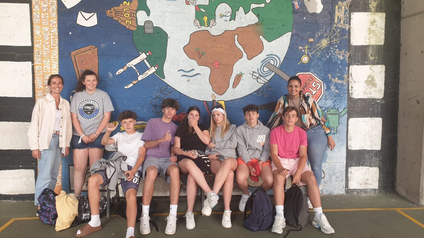 Un groupe d’élèves devant une fresque représentant la carte du monde
