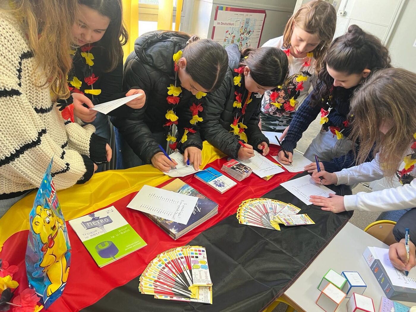 Des élèves écrivent sur des cartes autour d’une table couverte d’un drapeau