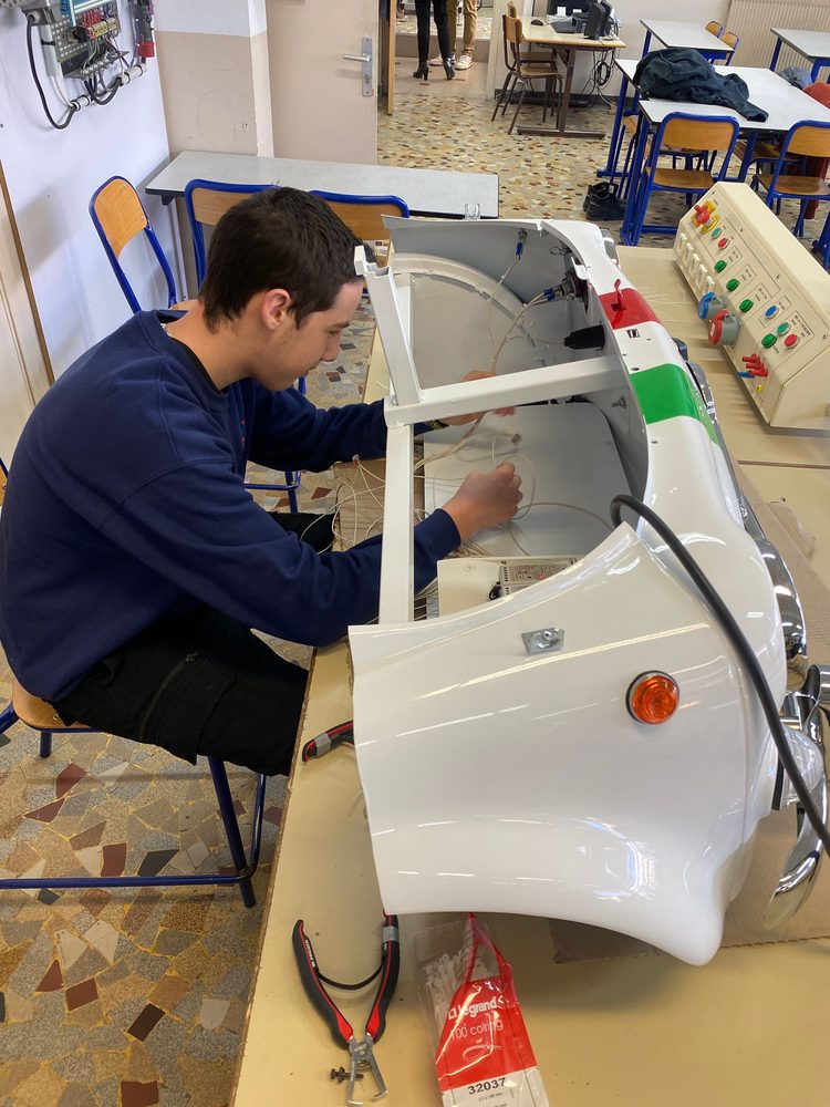 Un élève câble une maquette à l’atelier d’électricité