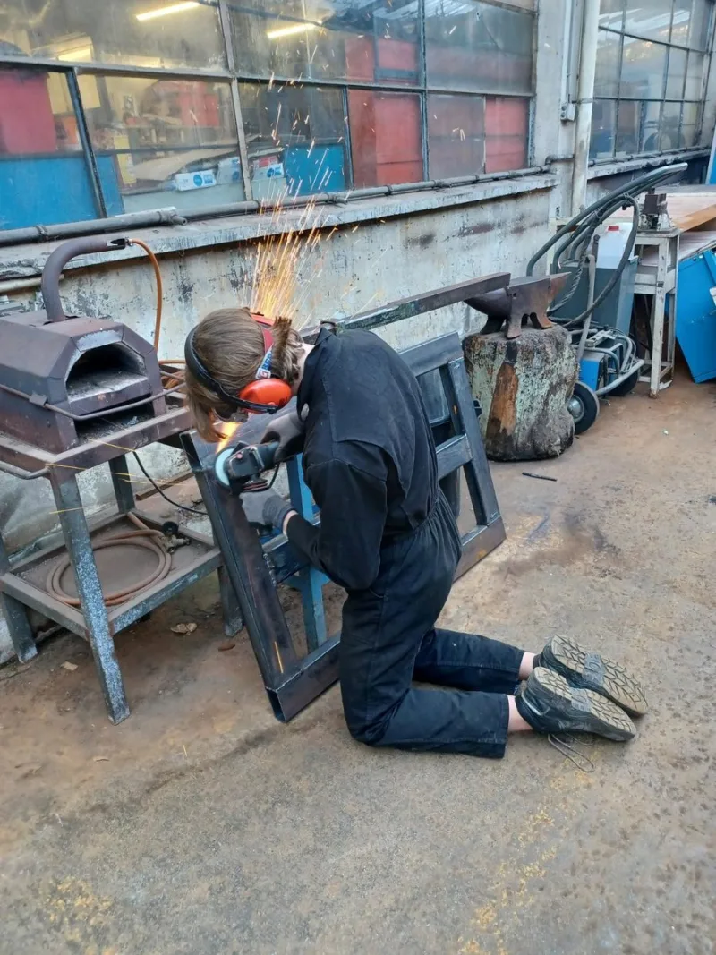 Meulage d’une pièce métallique à l’atelier, sous une gerbe d’étincelles