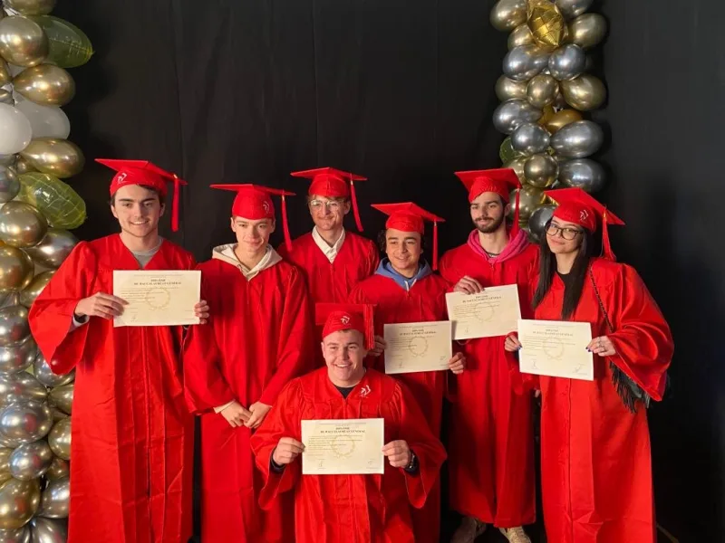 Sept bacheliers de la voie générale en toge rouge, leur diplôme en main